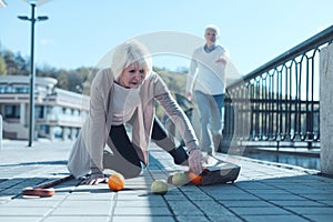 Scared woman dropping groceries while falling to ground