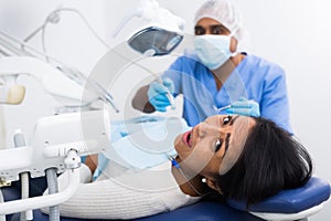 Scared woman lying on dentist chair during dental treatment