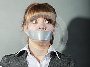 Scared woman with mouth taped shut. Censorship.