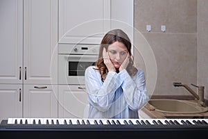 Scared woman pianist in amazement looks at a musical instrument, fear in the eyes of a musician