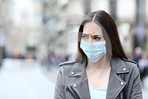 Scared woman with protective mask avoiding contagion on street photo