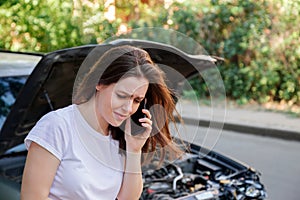 Scared woman in stress after auto crash calling to auto insurance for help. Driver woman crying in front of wrecked car