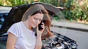 Scared woman in stress after auto crash calling to auto insurance for help. Driver woman crying in front of wrecked car in car