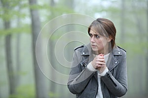 Scared woman walking alone in a foggy forest