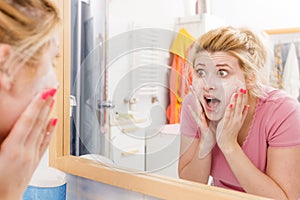 Scared woman washing her face under sink