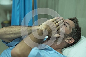 Scared and worried man hospitalized - attractive injured man lying on hospital bed receiving treatment feeling sick after