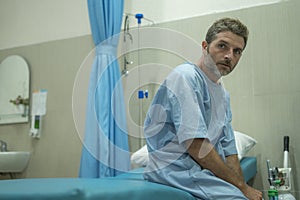 Scared and worried man hospitalized - attractive injured man sitting on hospital bed receiving treatment feeling sick and unwell