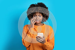 Scared young black woman looking at cell phone screen