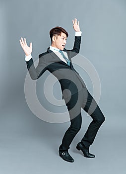 Scared young business man standing before gray background