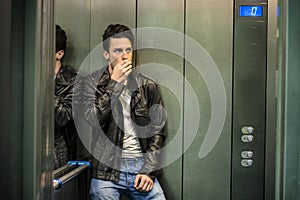 Scared young man desperate in stuck elevator photo