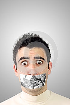 Scared young man having gray duct tape on mouth