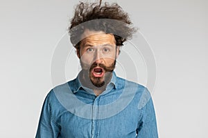 Scared young man with long beard opening mouth and shouting