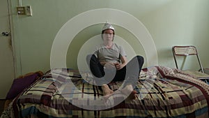 Scared young man wearing tin foil hat and panicking in the bedroom