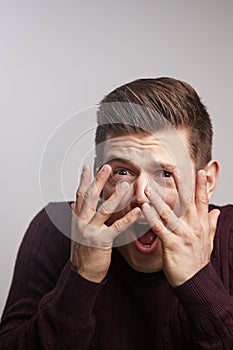 Scared young white man looking through his fingers