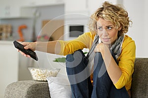 Scared young woman holding remote