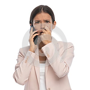 Scared young woman in pink jacket talking on the phone