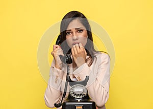 Scared young woman talking on the old rotary telephone