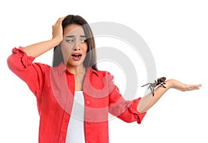 Scared young woman with tarantula on background. Arachnophobia fear of spiders