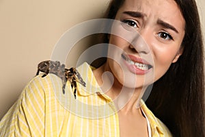 Scared young woman with tarantula on background. Arachnophobia fear of spiders