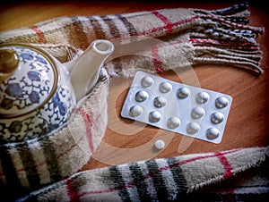 A scarf surrounds to a teapot along with capsules, concept palliative care