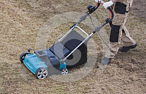 Scarifying lawn with scarifier, Man gardener scarifies the lawn and removal of old grass