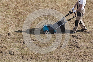Scarifying lawn with scarifier, Man gardener scarifies the lawn and removal of old grass