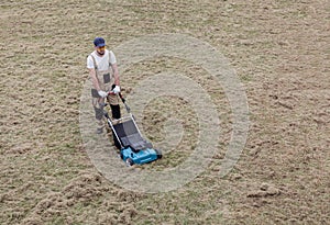 Scarifying lawn with scarifier, Man gardener scarifies the lawn and removal of old grass