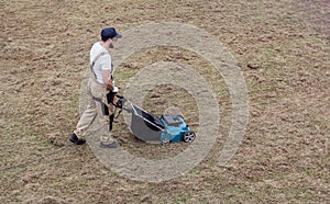 Scarifying lawn with scarifier, Man gardener scarifies the lawn and removal of old grass