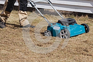 Scarifying lawn with scarifier, Man gardener scarifies the lawn and removal of old grass