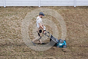 Scarifying lawn with scarifier, Man gardener scarifies the lawn and removal of old grass