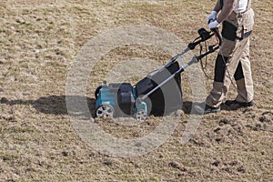 Scarifying lawn with scarifier, Man gardener scarifies the lawn and removal of old grass