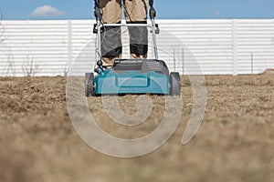 Scarifying lawn with scarifier, Man gardener scarifies the lawn and removal of old grass