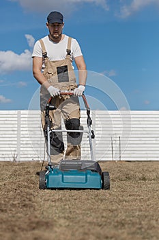 Scarifying lawn with scarifier, Man gardener scarifies the lawn and removal of old grass