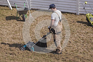 Scarifying lawn with scarifier, Man gardener scarifies the lawn and removal of old grass