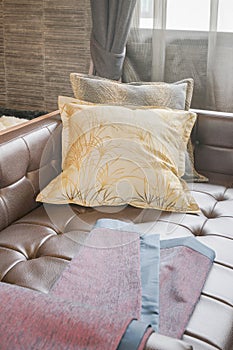 Scarlet fabric on leather sofa-bed with yellow pillow in living room