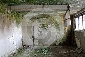 Scarry creepy green moss covered walls of dilapidated room with broken metal industrial ventilation at abandoned military complex