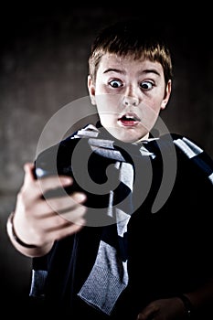 Scarry teenager looking at his mobile phone