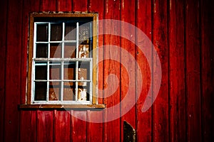 Scary abandoned house with old peeling red wooden wall and grunge broken window under dramatic lighting