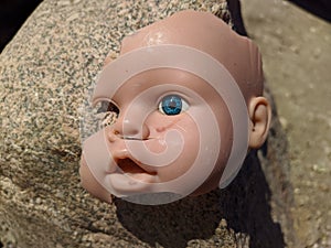 scary and broken doll face with one blue eye on a background of stone