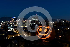 Scary carved pumpkin with a city view background