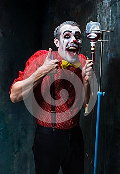 The scary clown and drip with blood on dack background. Halloween concept