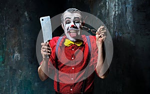 The scary clown holding a knife on dack. Halloween concept