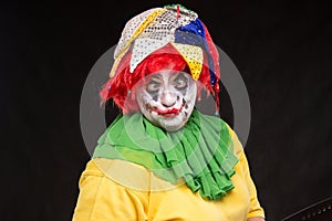 Scary clown joker with a smile and red hair on a black background