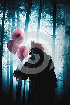 Scary clowns holding balloons in a forest