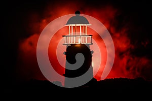 Scary dark ominous lighthouse behind a red fire background. Lighthouse at dusk/ Sunset Light House/ Light house at sunset. Decorat