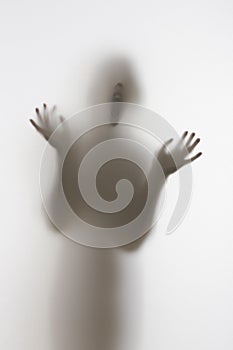 Scary diffuse human face and hands silhouette shouting behind a curtain