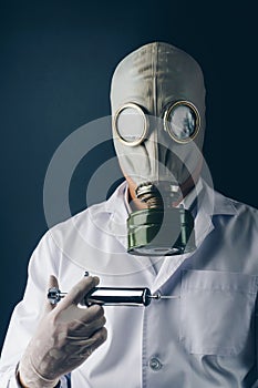 A scary doctor in gas mask with a big stainless steel syringe