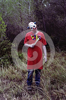 Scary evil clown with a knife in the woods