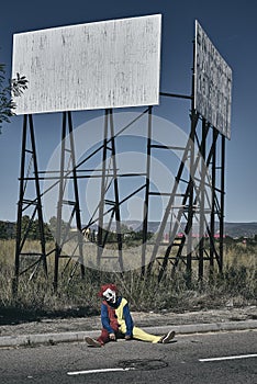 Scary evil clown sitting on the ground