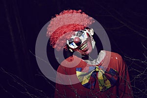 Scary evil clown in the woods at night